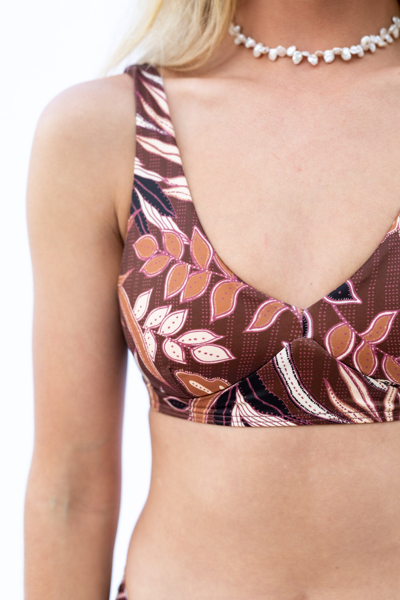 Close up of a model wearing a shell necklace and the Elation Nias Surf top